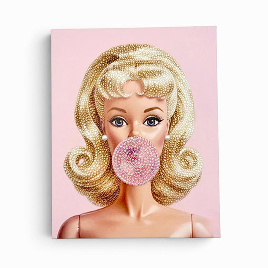 A square bedazzled canvas featuring a Barbie with blue eyes blowing a pink bubblegum bubble, set against a light pink background.
